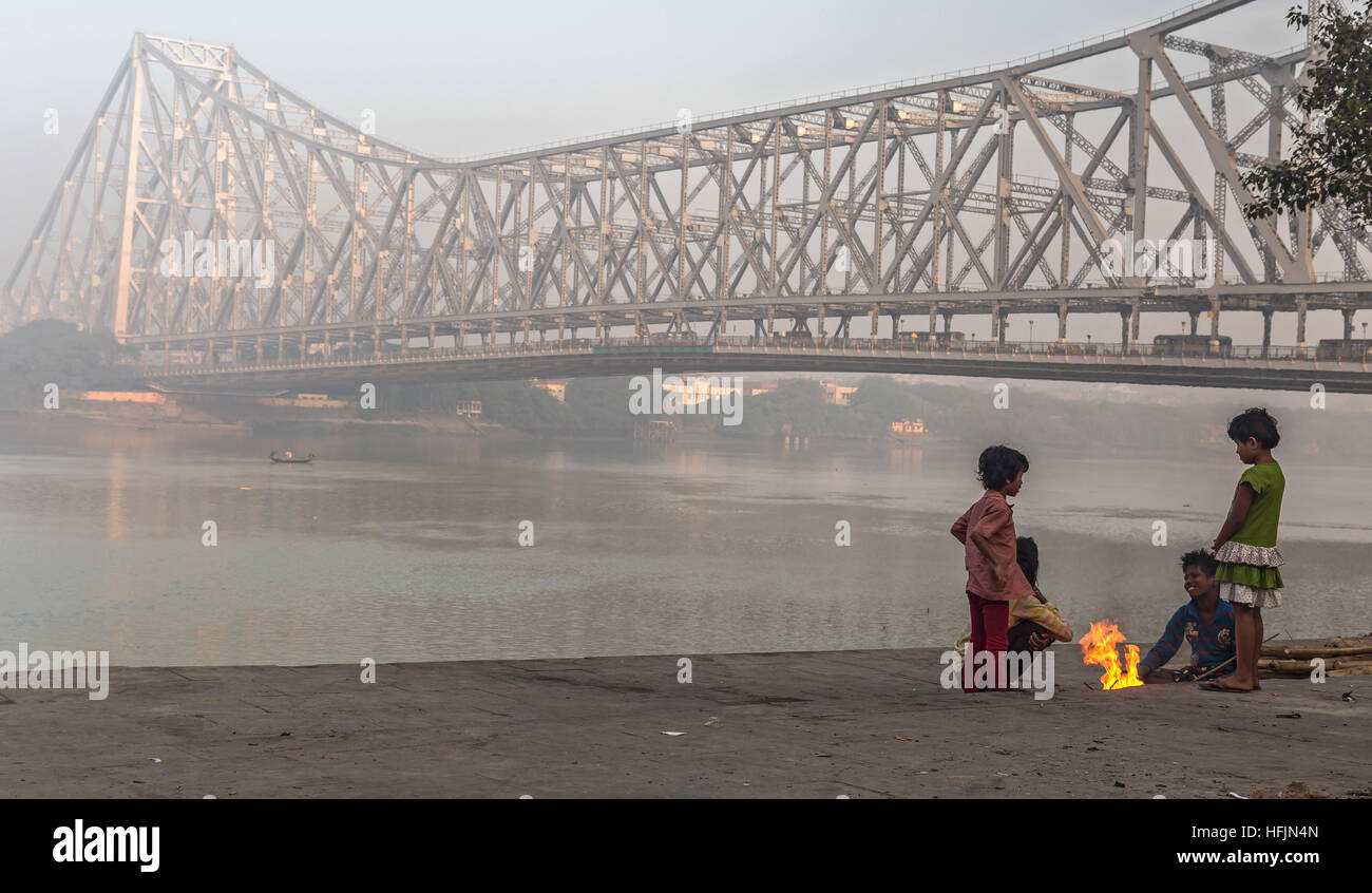 Bambini di strada tenete in caldo su un freddo inverno nebbiosa mattina a Mallick ghat vicino a quella di Howrah bridge presso la banca di fiume Hooghly. Foto Stock