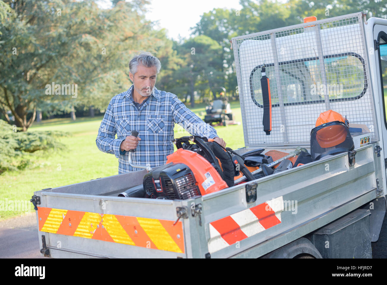 L'uomo il caricamento di attrezzature da giardinaggio nel veicolo Foto Stock