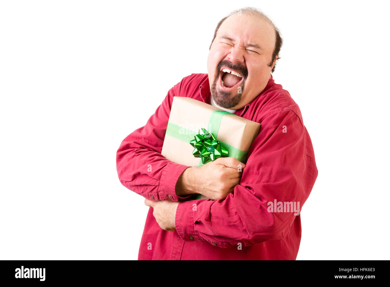 Felice urlando uomo in rosso azienda dono avvolto in carta oro e nastro di verde su sfondo bianco Foto Stock