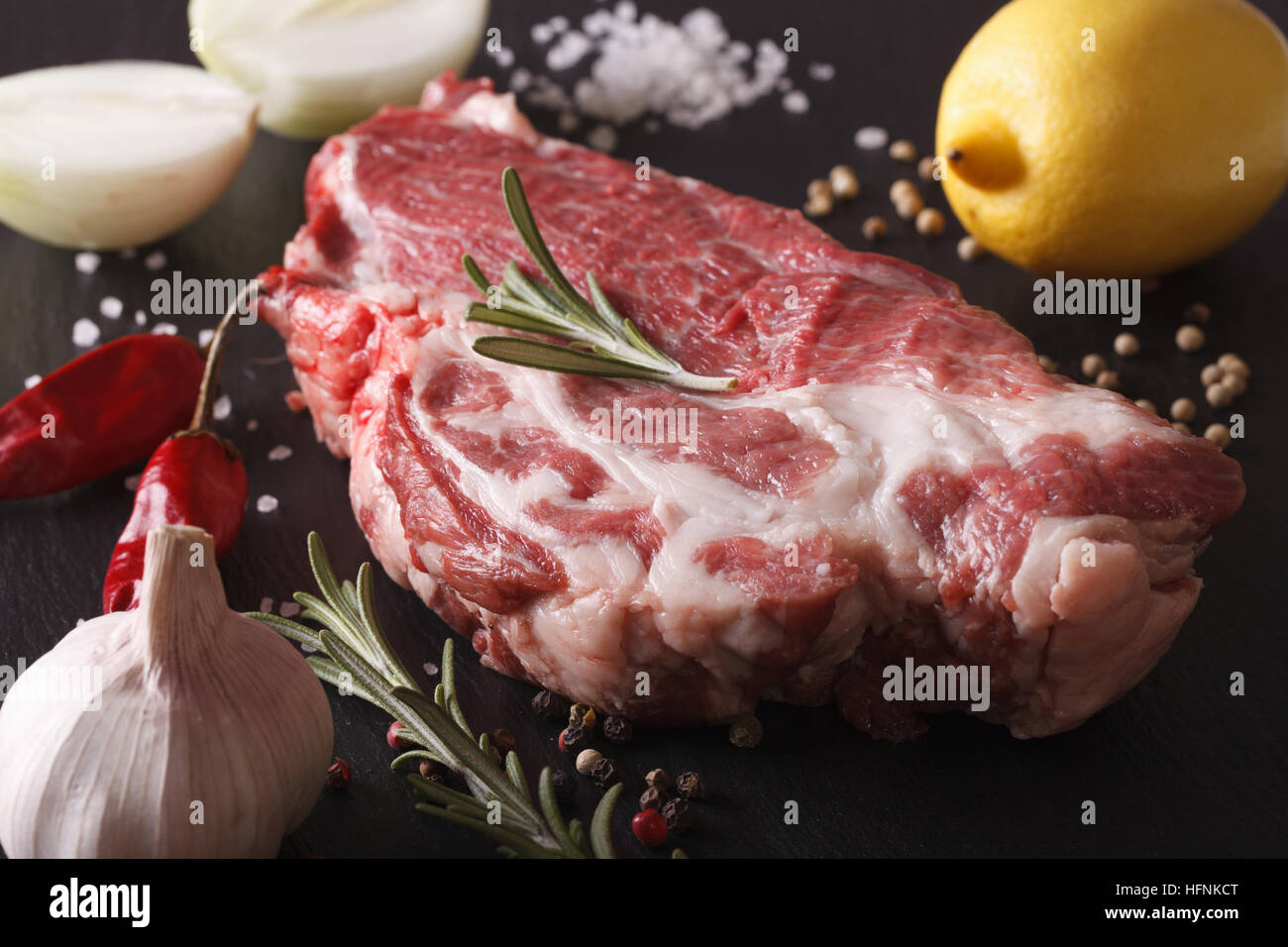 Pezzo di collo di maiale cruda e ingredienti macro su un scheda di ardesia. Posizione orizzontale Foto Stock