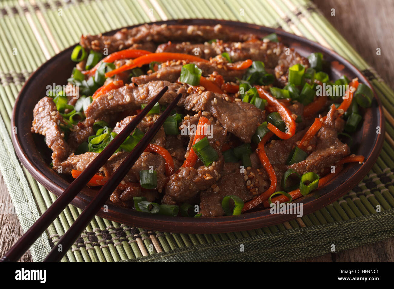 Cucina asiatica: fettine di carne fritti con sesamo e carota close-up su una piastra orizzontale. Foto Stock