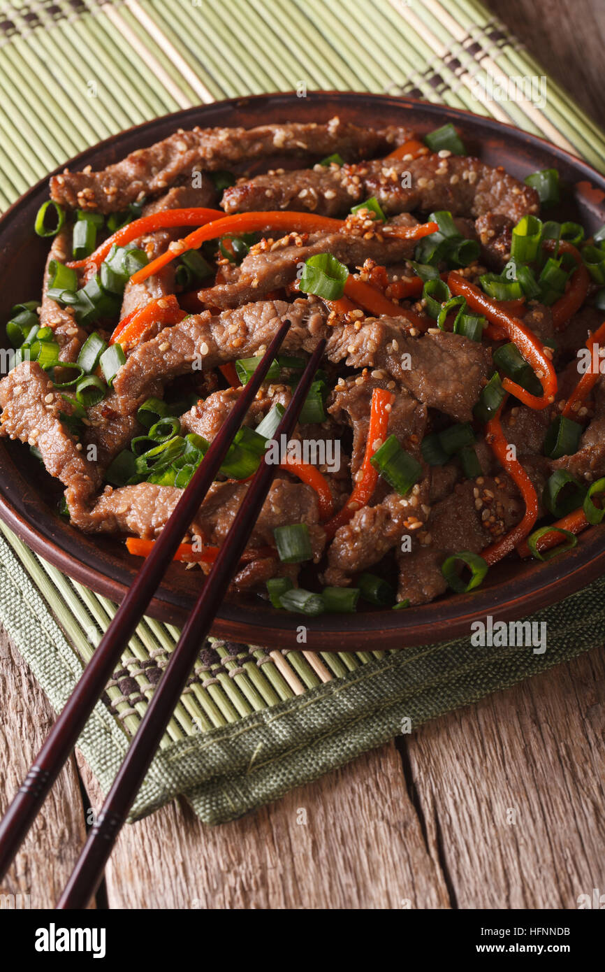 Cibo asiatico: fettine di carne fritti con semi di sesamo e carote closeup. In verticale Foto Stock