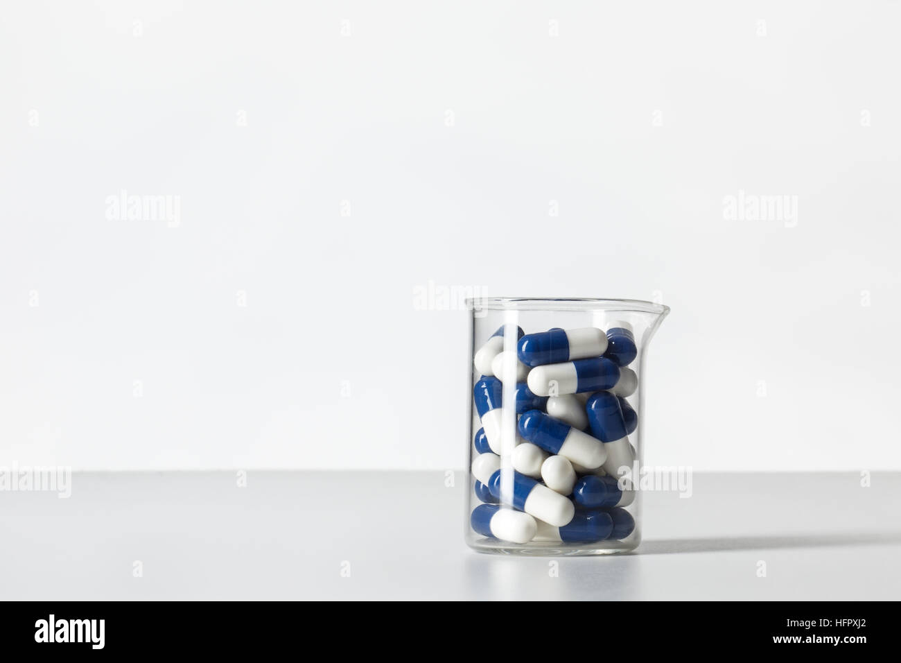 Becher tarato con pillole all'interno, girato in studio su sfondo bianco Foto Stock