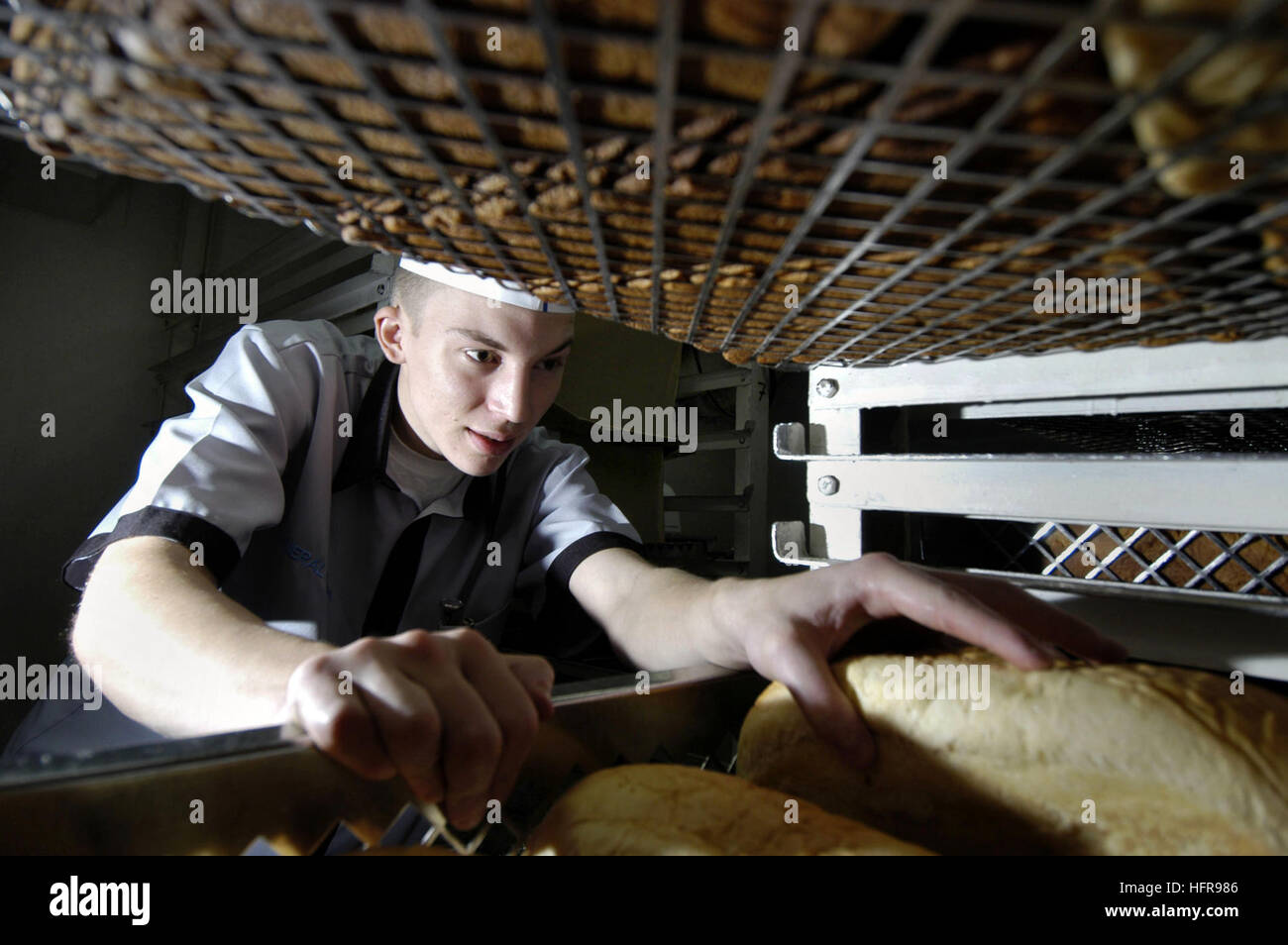 051201-N-8854R-028 sul Mare del Sud della Cina (dec. n. 1, 2005) - specialista culinaria marinaio Clayton Roberts di Londra, Ky., recupera una pagnotta di pane dalla camera del pane a bordo alimentato convenzionalmente portaerei USS Kitty Hawk (CV 63). Kitty Hawk's Bakery produce più di 3.000 cena rotoli, 3.000 i cookie, 2.000 torte e 900 pagnotte di pane al giorno per un equipaggio di circa 5.300. Kitty Hawk e avviato Carrier aria Wing cinque (CVW-5) stanno attualmente conducendo operazioni nell'Oceano Pacifico occidentale. Stati Uniti Navy foto dal fotografo di Mate Airman Matteo Reinhardt (rilasciato) Navy US 051201-N-8854R- Foto Stock