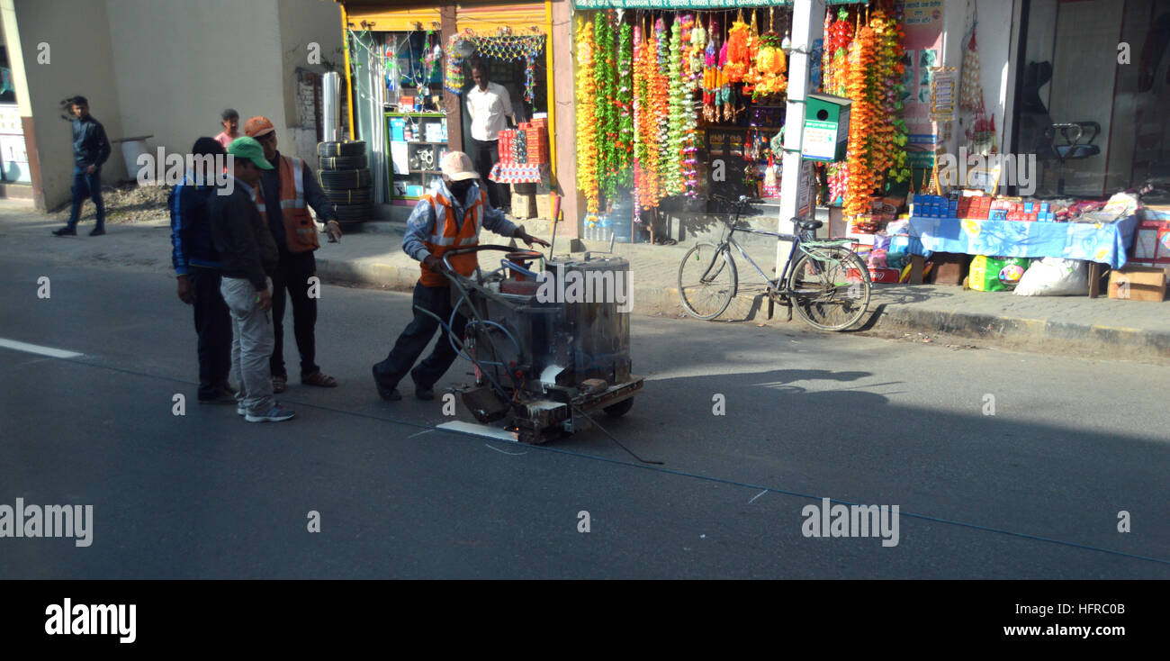 Strada nepalese di operai di manutenzione verniciatura linee bianche in mezzo alla strada a Kathmandu, Nepal, Asia. Foto Stock