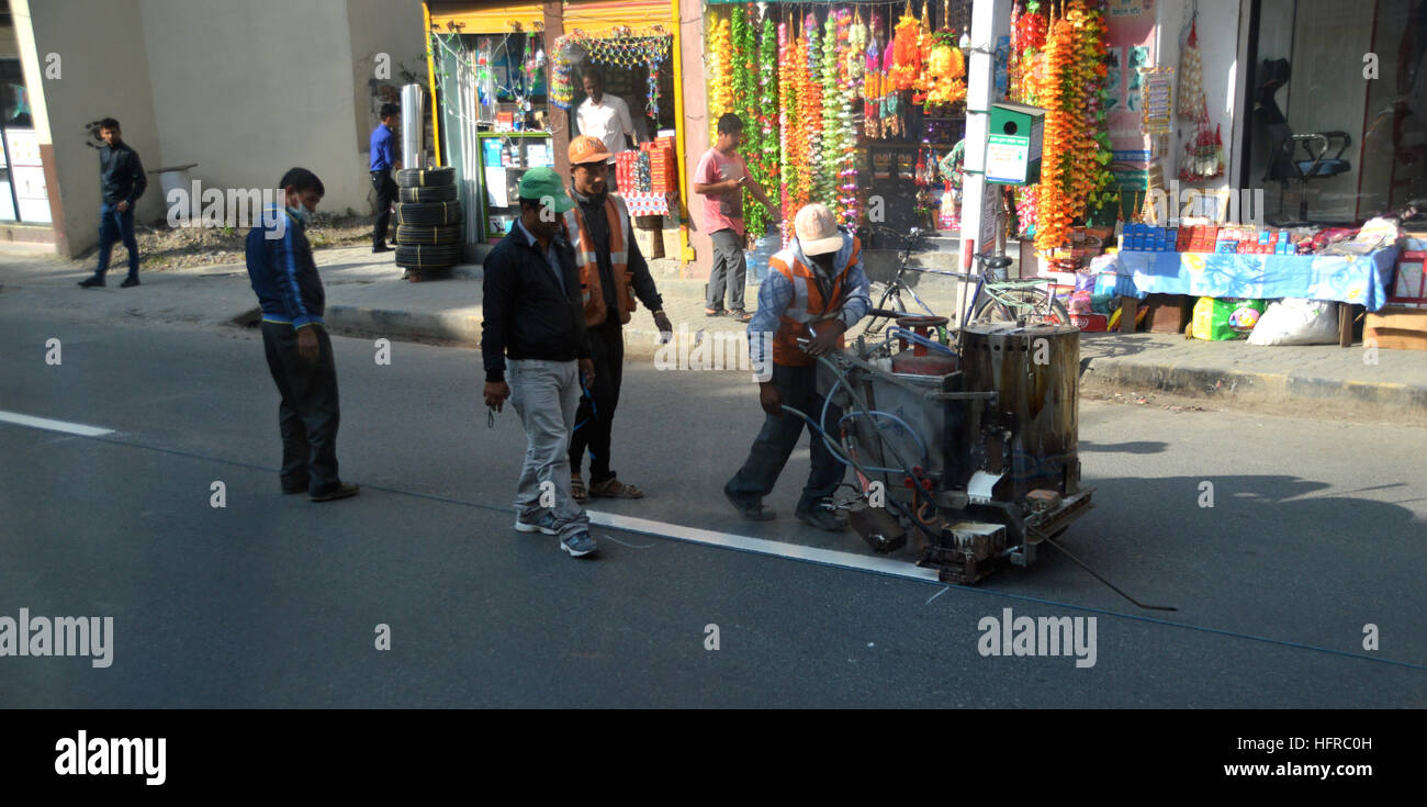 Strada nepalese di operai di manutenzione verniciatura linee bianche in mezzo alla strada a Kathmandu, Nepal, Asia. Foto Stock
