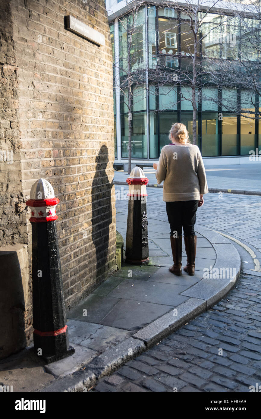 Una donna in piedi su un angolo di strada a Londra avente una sigaretta Foto Stock