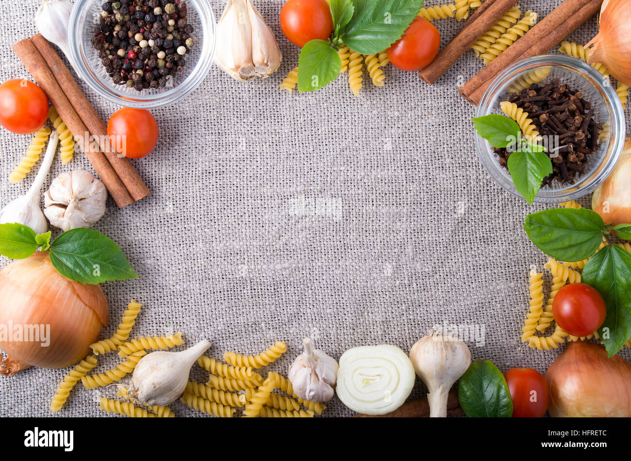 Vista superiore degli ingredienti per un pasto in cucina su uno sfondo di tessuto grigio con uno spazio vuoto al centro Foto Stock