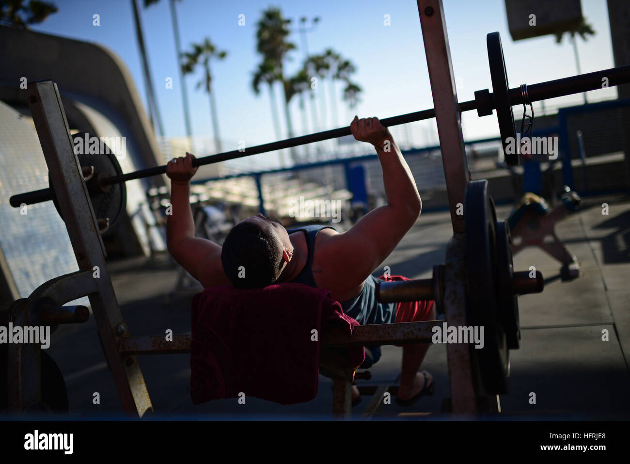 L'uomo facendo barbell pressa da banco in palestra all'aperto presso la spiaggia di Venice, California. Foto Stock