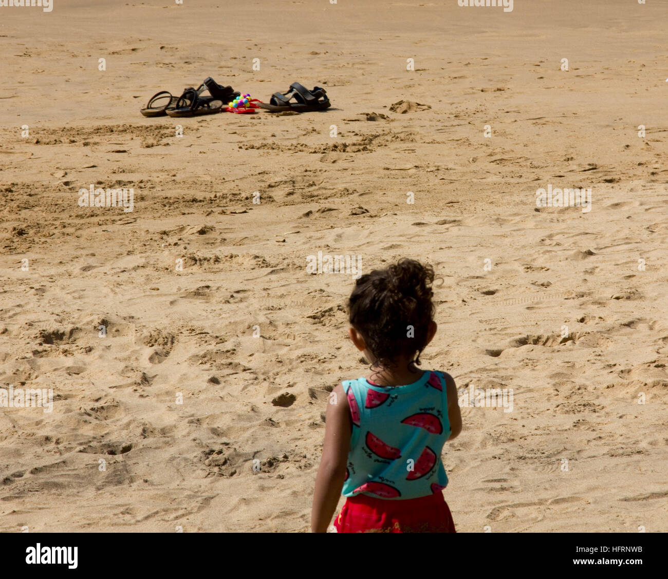 Baby girl giocando da solo sulla spiaggia. Girato a Anjuna Beach a nord Goa, India. Foto Stock