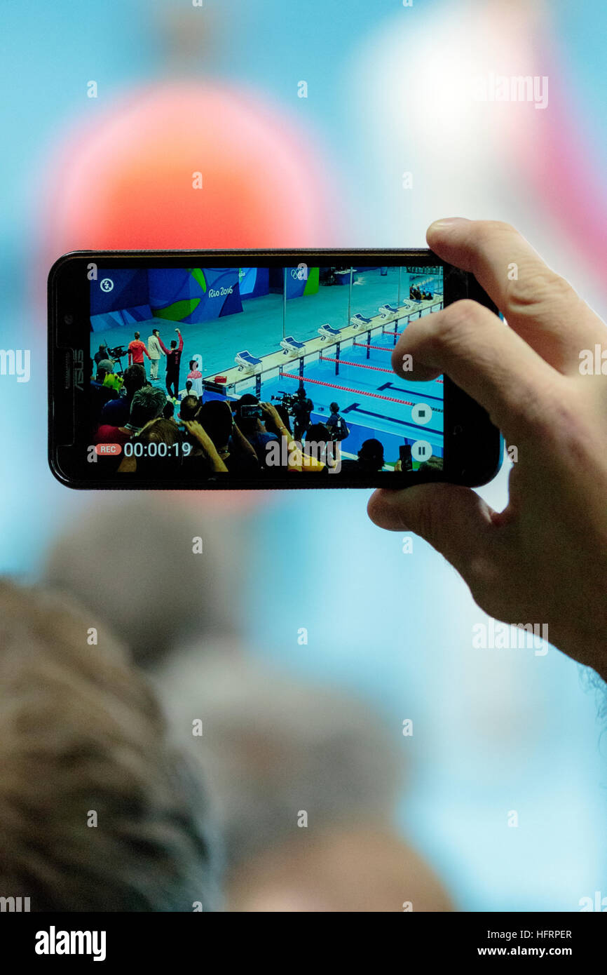 Rio de Janeiro, Brasile. Il 9 agosto 2016. Spettatore utilizzando il telefono cellulare per fotografia Michael Phelps (USA) la medaglia d'oro della Uomini 200m butte Foto Stock