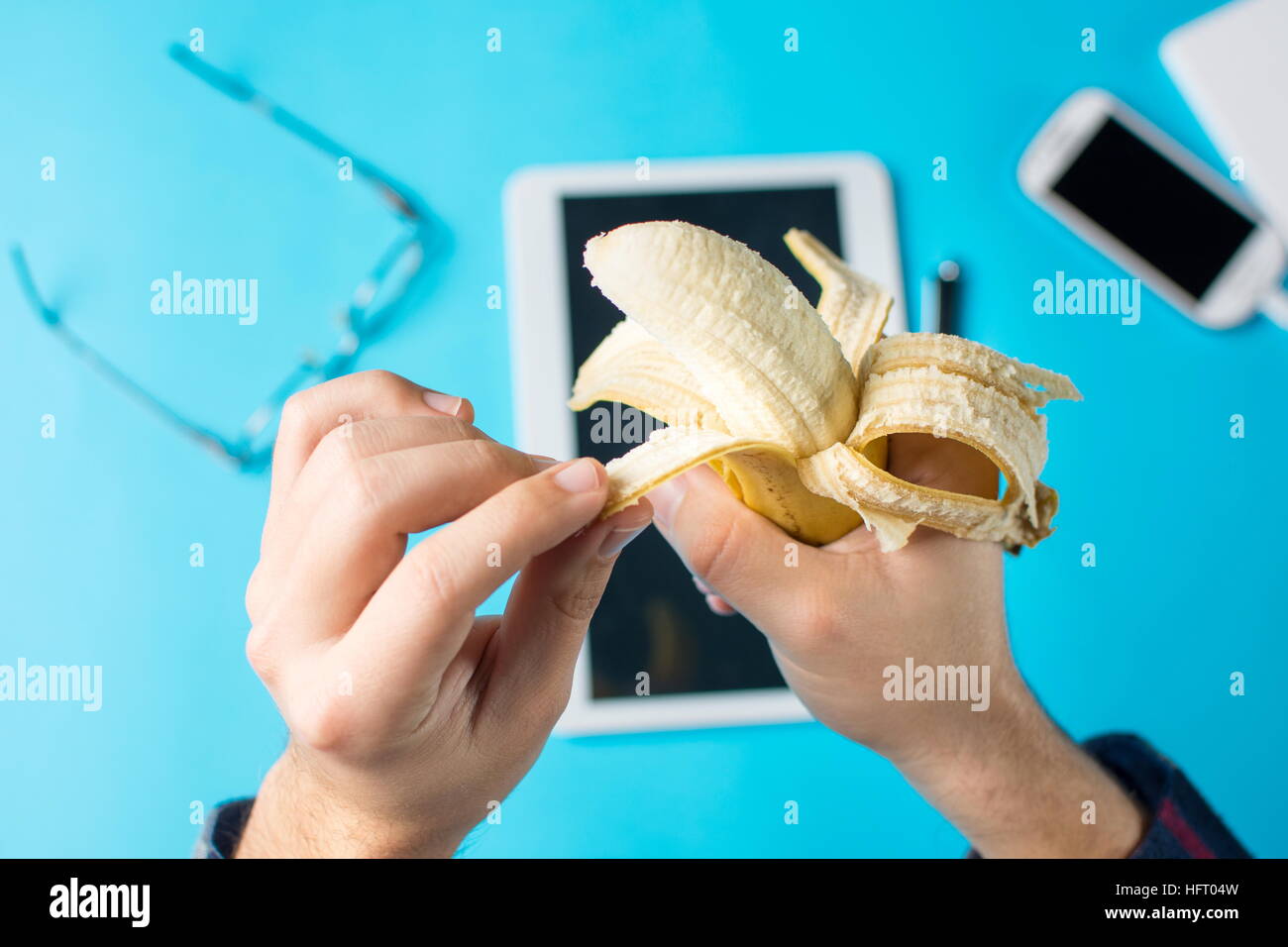 Maschio peeling a mano una banana al lavoro in ufficio Foto Stock