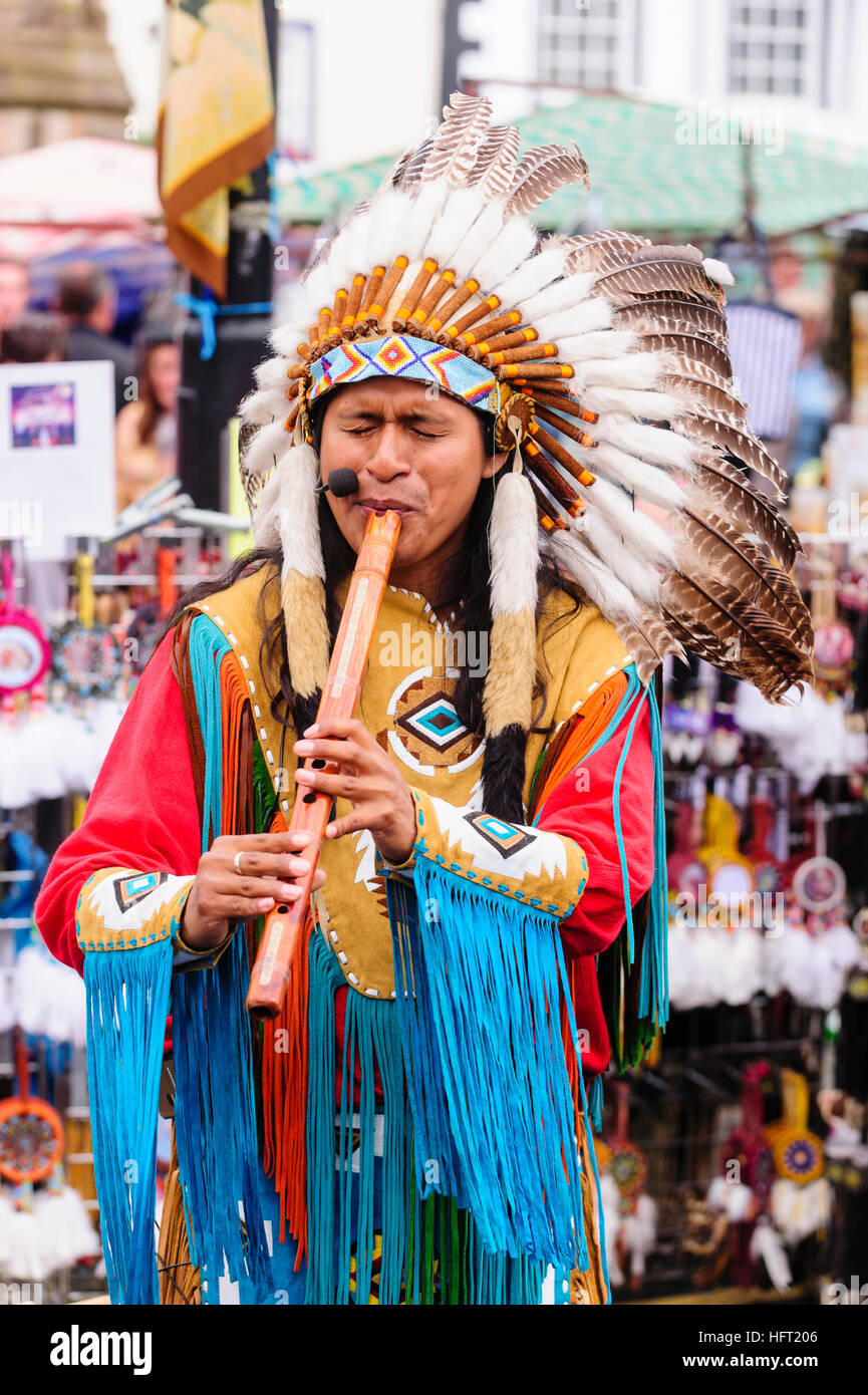 Nativo (Sud) American indossa un costume tradizionale e selvaggina di penna copricapo giocando un flauto in legno Foto Stock