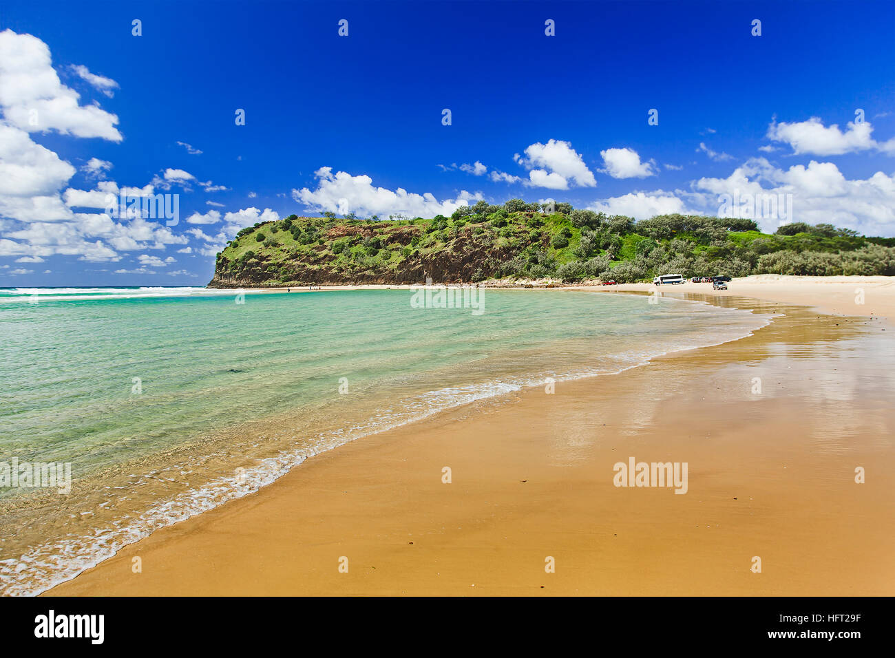 Ampia pulita spiaggia sabbiosa su Fraser Island vicino a Indian Head su un estate giornata di sole. Onda liscia lavaggi vuoto sabbia sotto il cielo blu. Foto Stock