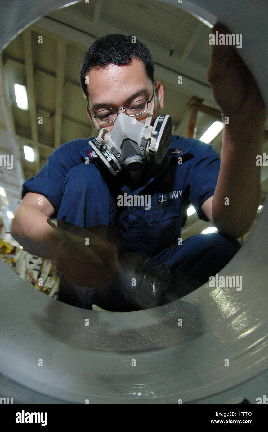 Un Aviation Support Equipment Technician a bordo della USS Kitty Hawk (CV 63) esegue la manutenzione di autocarri antincendio e trattori in cabina di pilotaggio mediante verniciatura dei cerchi per prevenire la corrosione, garantendo un movimento sicuro ed efficace dell'aeromobile durante le operazioni di volo. Foto Stock