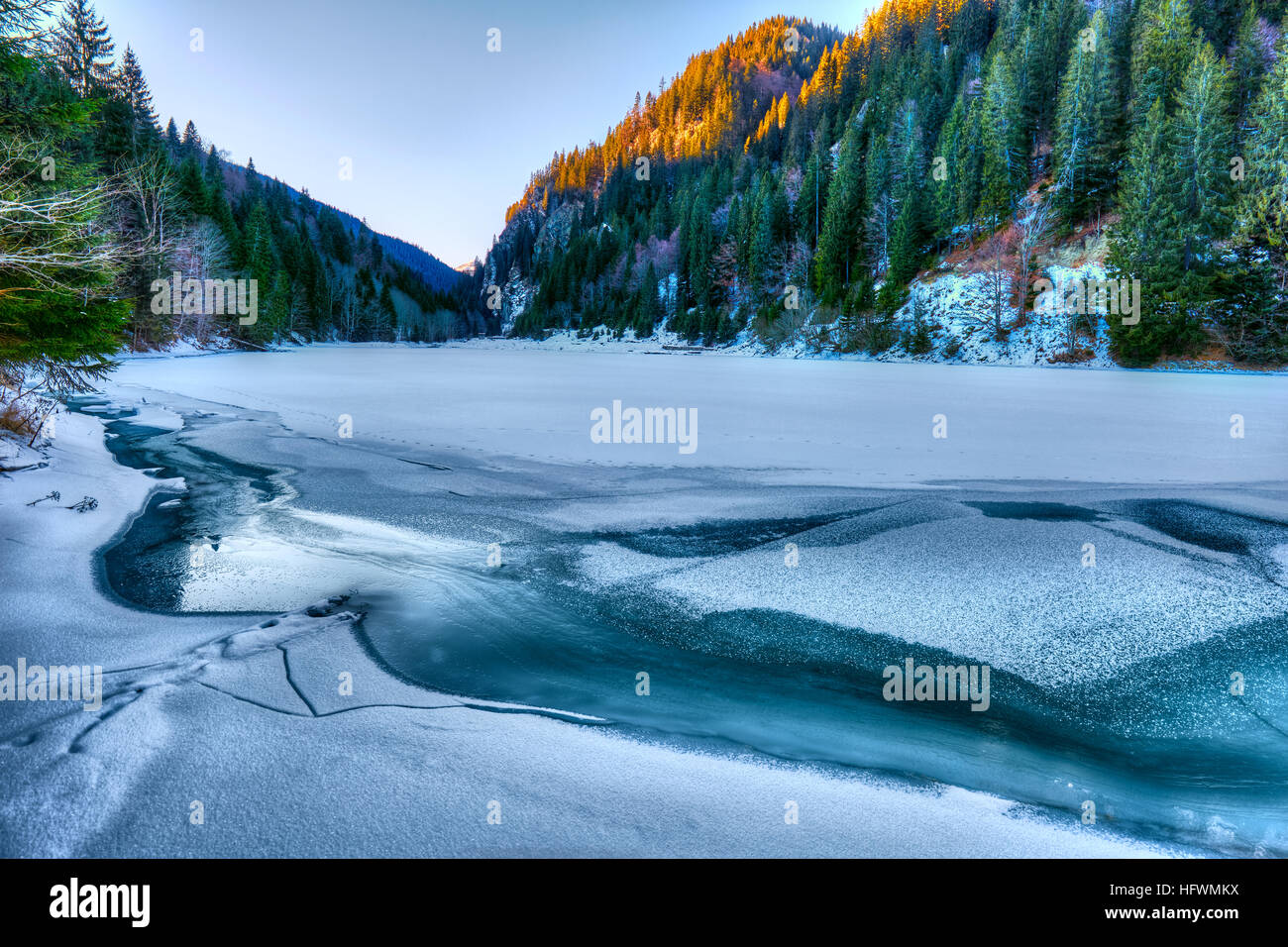 Paesaggio con un lago ghiacciato e le montagne con alberi di pino Foto Stock