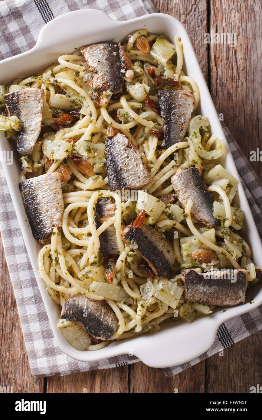 Spaghetti con le sardine, finocchio, uvetta, noci e prezzemolo e chiudere fino in una teglia sul tavolo. vista verticale da sopra Foto Stock