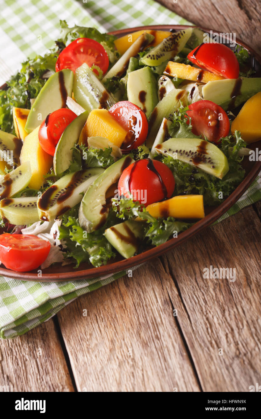 Vitamina insalata di mango, avocado, kiwi, pomodori e lattuga su una piastra di close-up verticale. Foto Stock