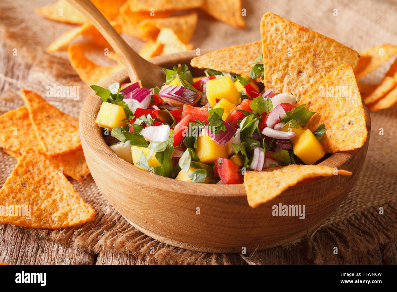 Con salsa di mango, peperoni, il coriandolo e la cipolla vicino fino in una ciotola e nachos. Posizione orizzontale Foto Stock