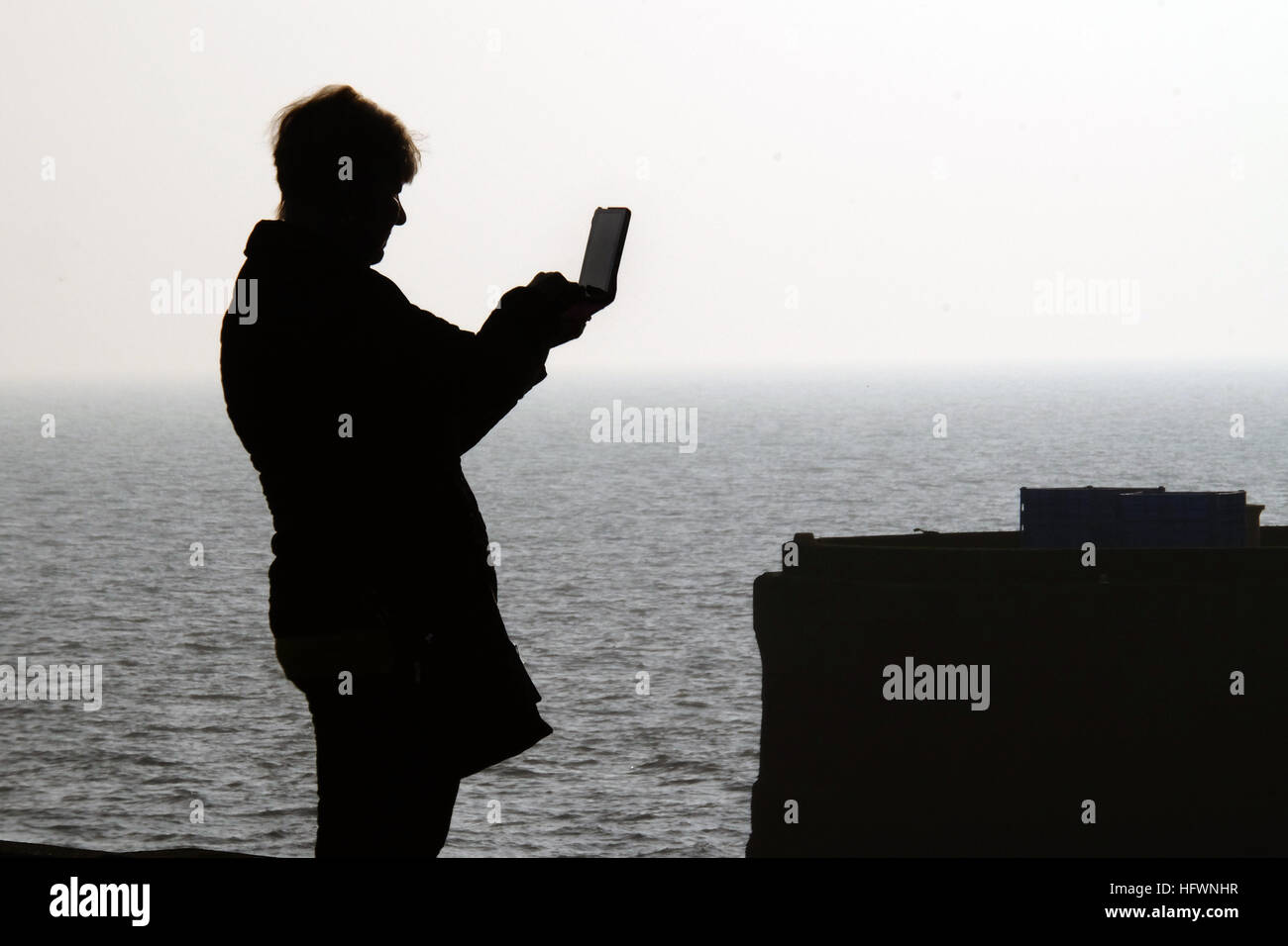 Donna di scattare le foto con il computer tablet sulla parete del porto. Foto Stock