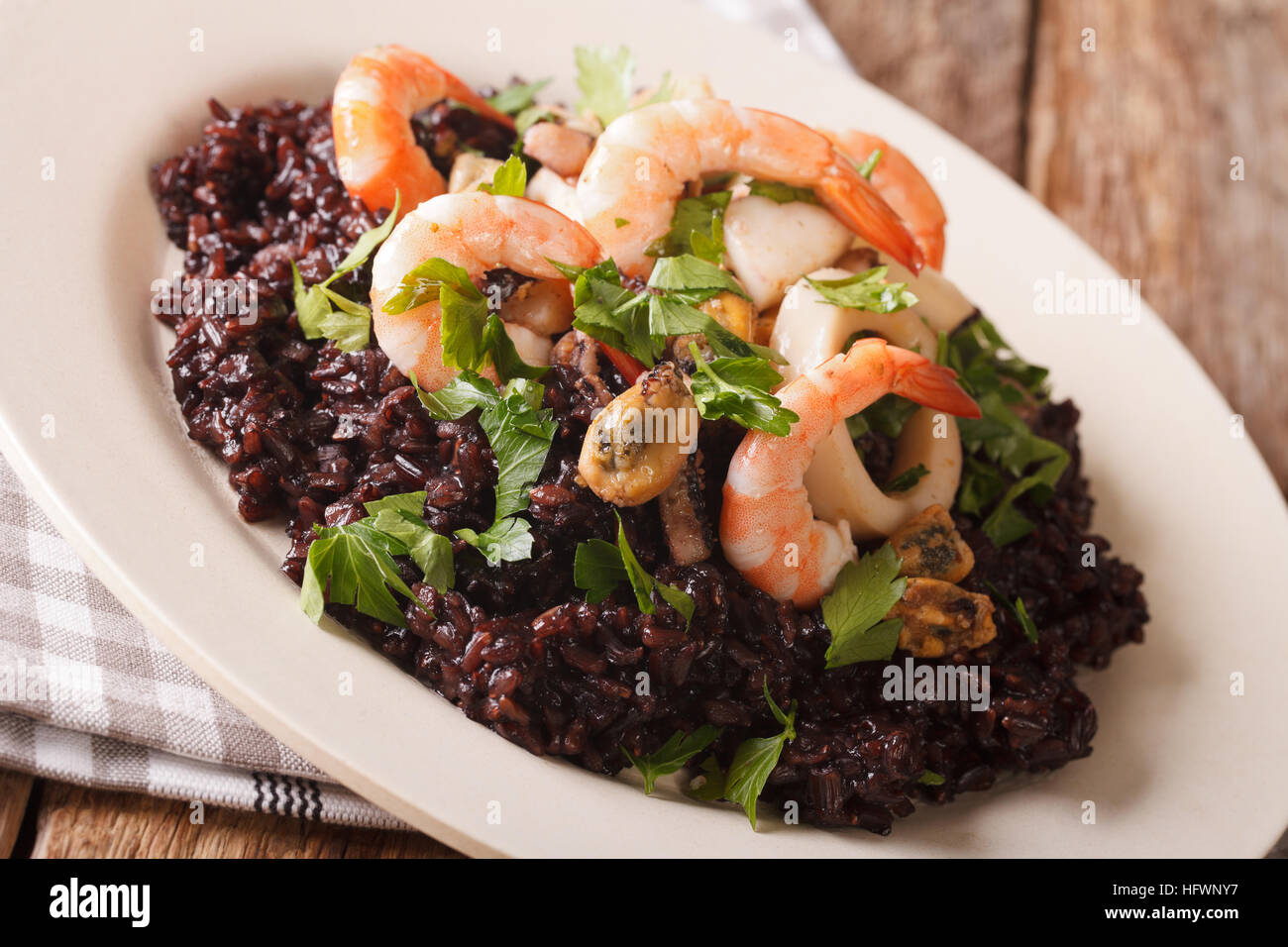 Wild il riso nero con gamberi, calamari, cozze e capesante close up su una piastra sul tavolo. Posizione orizzontale Foto Stock