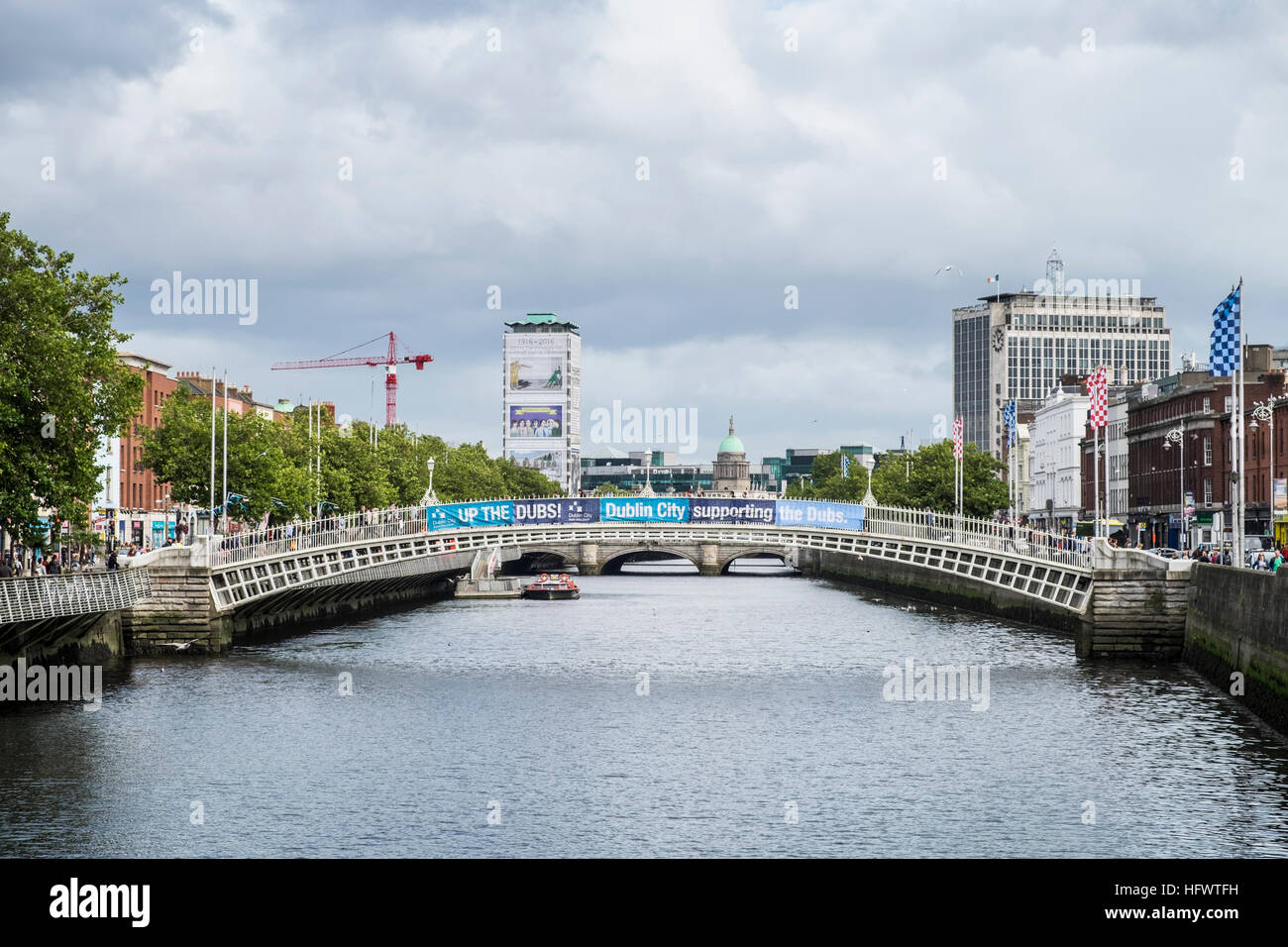 Guardando verso Est lungo il fiume Liffey, halfpenny bridge con striscioni il supporto di Dublins football team, Dublino, Irlanda Foto Stock