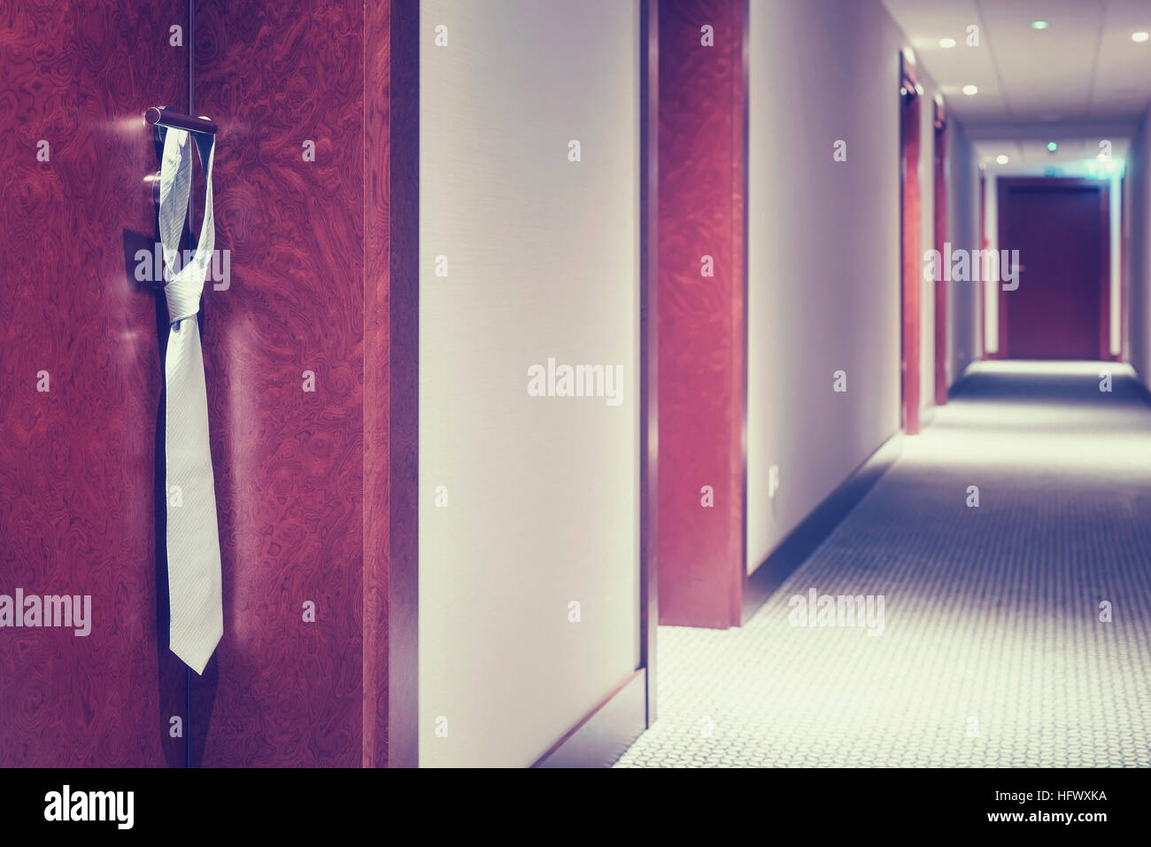 Vintage stilizzata cravatta Argento appeso su un hotel chiuso maniglia della porta. Foto Stock