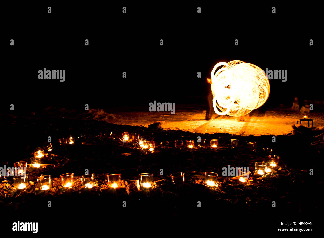 Forma di cuore di candele accese sul terreno su uno sfondo di fire show. Foto Stock