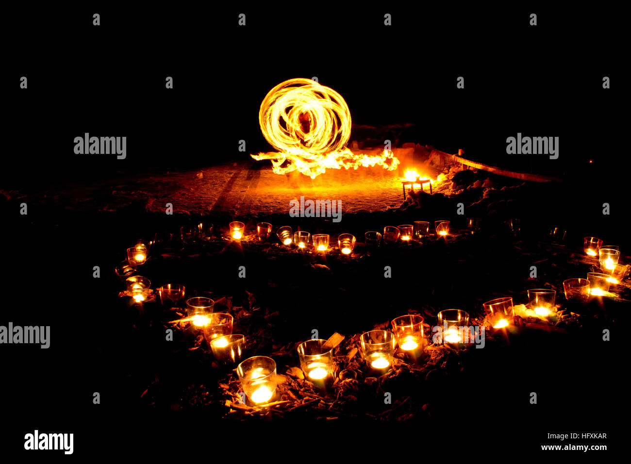 Forma di cuore di candele accese sul terreno su uno sfondo di fire show. Foto Stock
