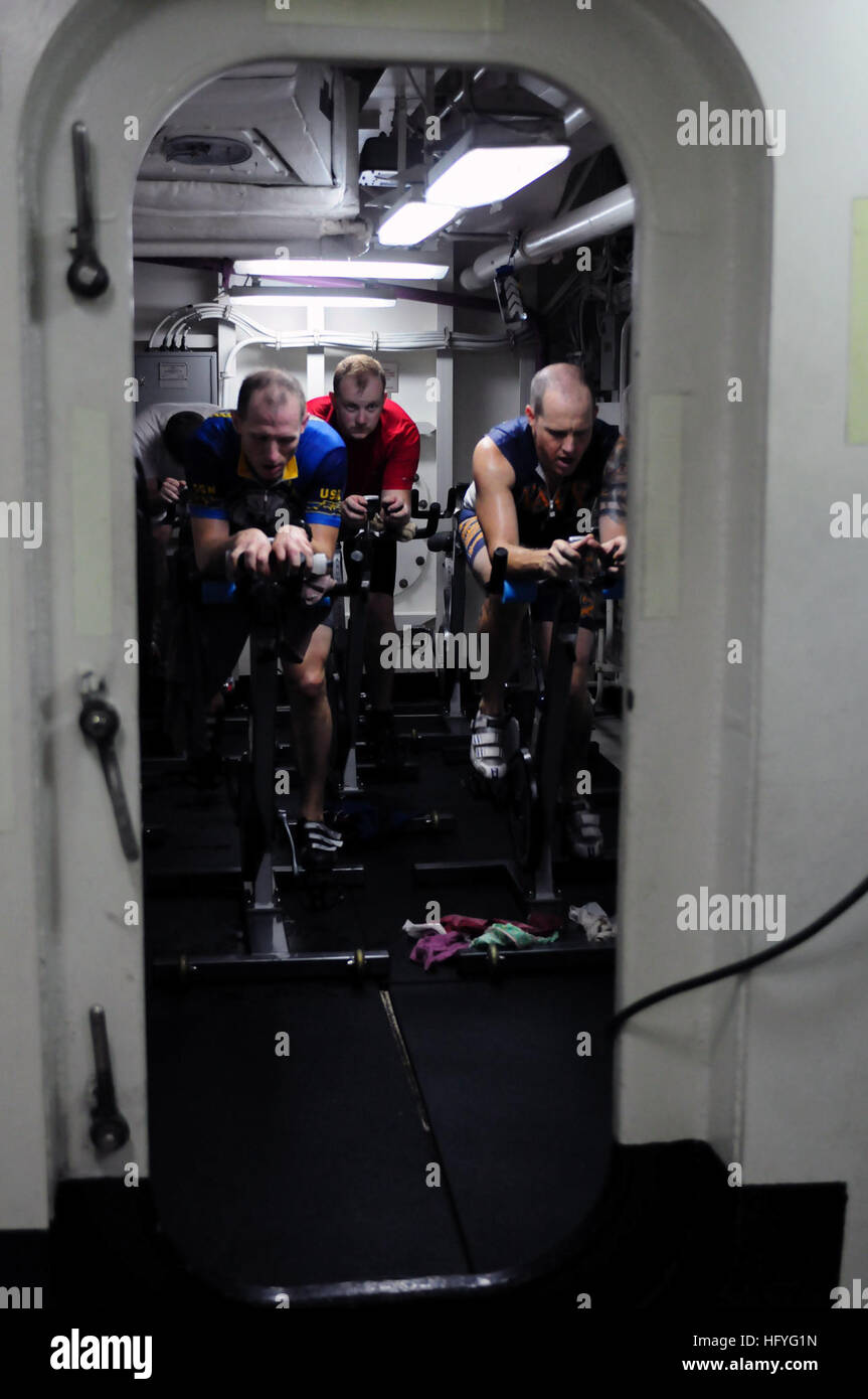 Il tenente j.g. Il Ciad Haack, 33 e Master Chief Petty Officer Jim Ritch, un tecnico elettronico, 48, attraversare il giro di boa della bicicletta simulato corso porzione di una nave-board triathlon hanno completato insieme sulla portaerei USS Ronald Reagan (CVN 76). La nave-board triathlon incluso un 1 ora e dieci minuti di fila simulato, in luogo di un 2.4-miglio a nuotare, a 112 miglia moto simulato e naturalmente un 26.2 miglia di corsa. Ritch e Haack disposti per completare la 12 Ore di triathlon dopo un cambiamento nella nave del programma significava che non potevano competere nel Silverman Triathlon in Henderson, Nev. Ronald Reagan è Foto Stock