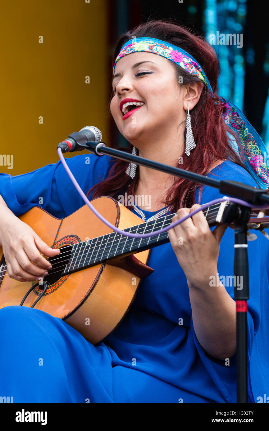 Columbian cantautore, cantante e chitarrista, Carolina Herrera in vestito blu, suonare la chitarra e cantare mentre è seduto su un palcoscenico open-air a Ramsgate. Foto Stock