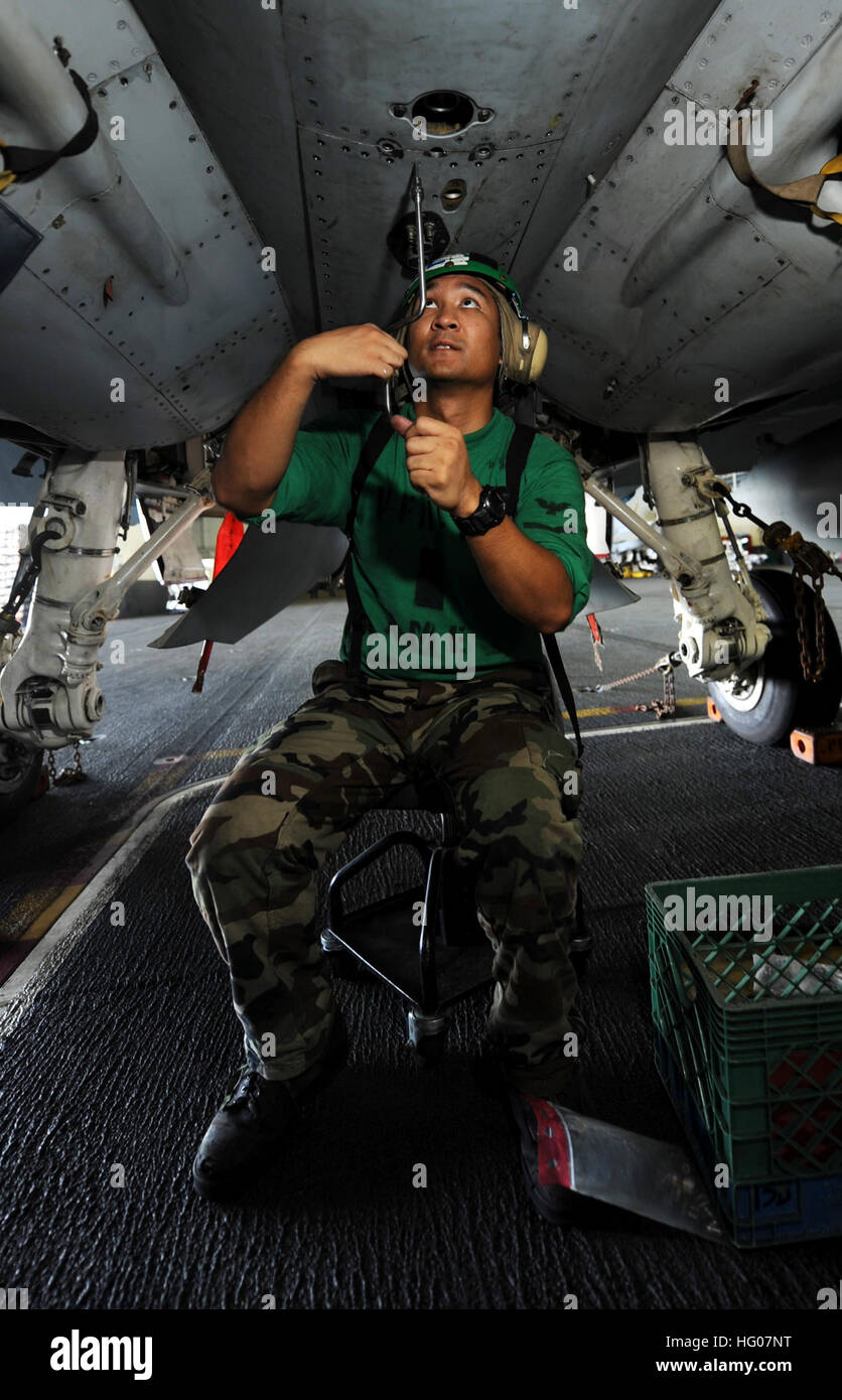 Un Aviation Structural Mechanic rimuove i pannelli su un F/A-18C Hornet a bordo della portaerei classe Nimitz John C. Stennis, schierato nella 5th Fleet statunitense conducendo operazioni di sicurezza marittima e missioni di supporto per le operazioni Enduring Freedom e New Dawn. Foto Stock