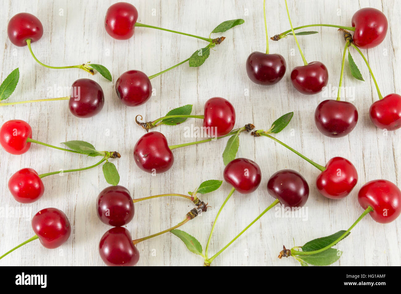 Grappolo di ciliege rosse sparse su un tavolo di legno Foto Stock