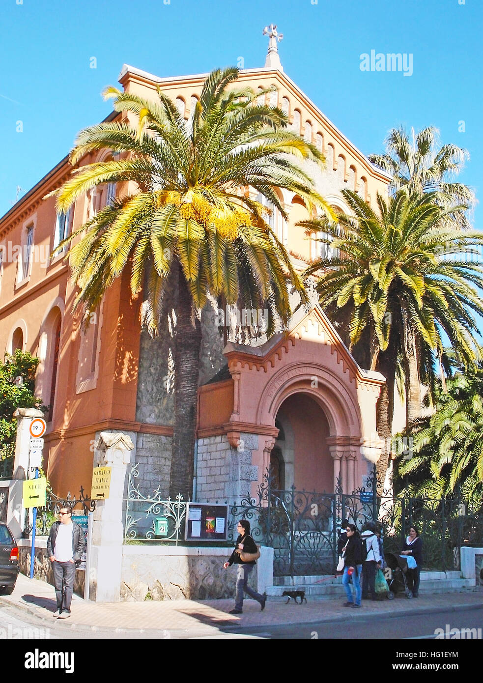 La facciata della Chiesa riformata è nascosta dietro le lussureggianti palme di Mentone, in Francia Foto Stock