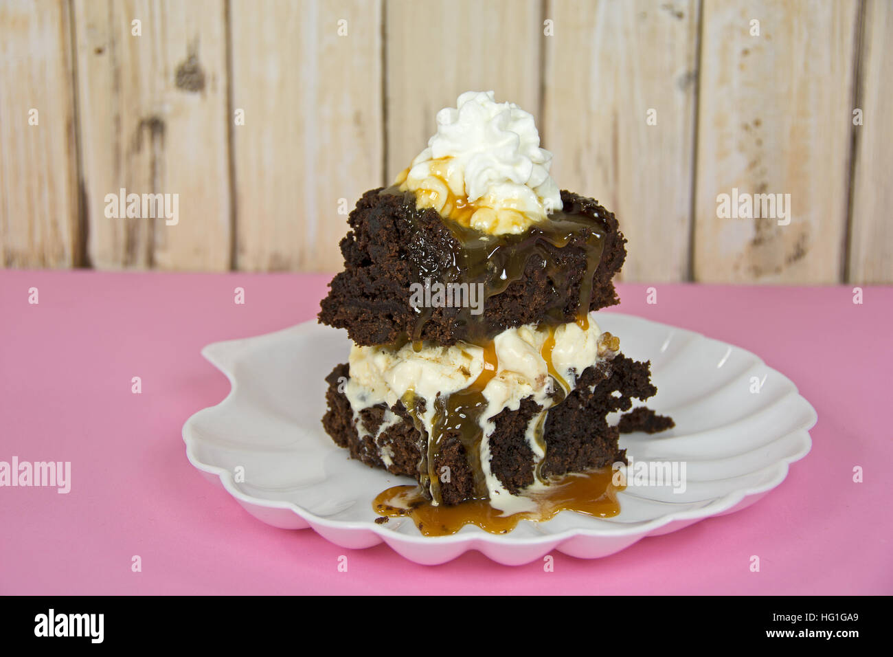 Brownie al cioccolato gelato di gocciolamento con salsa di caramello su bianco seashell piastra Foto Stock