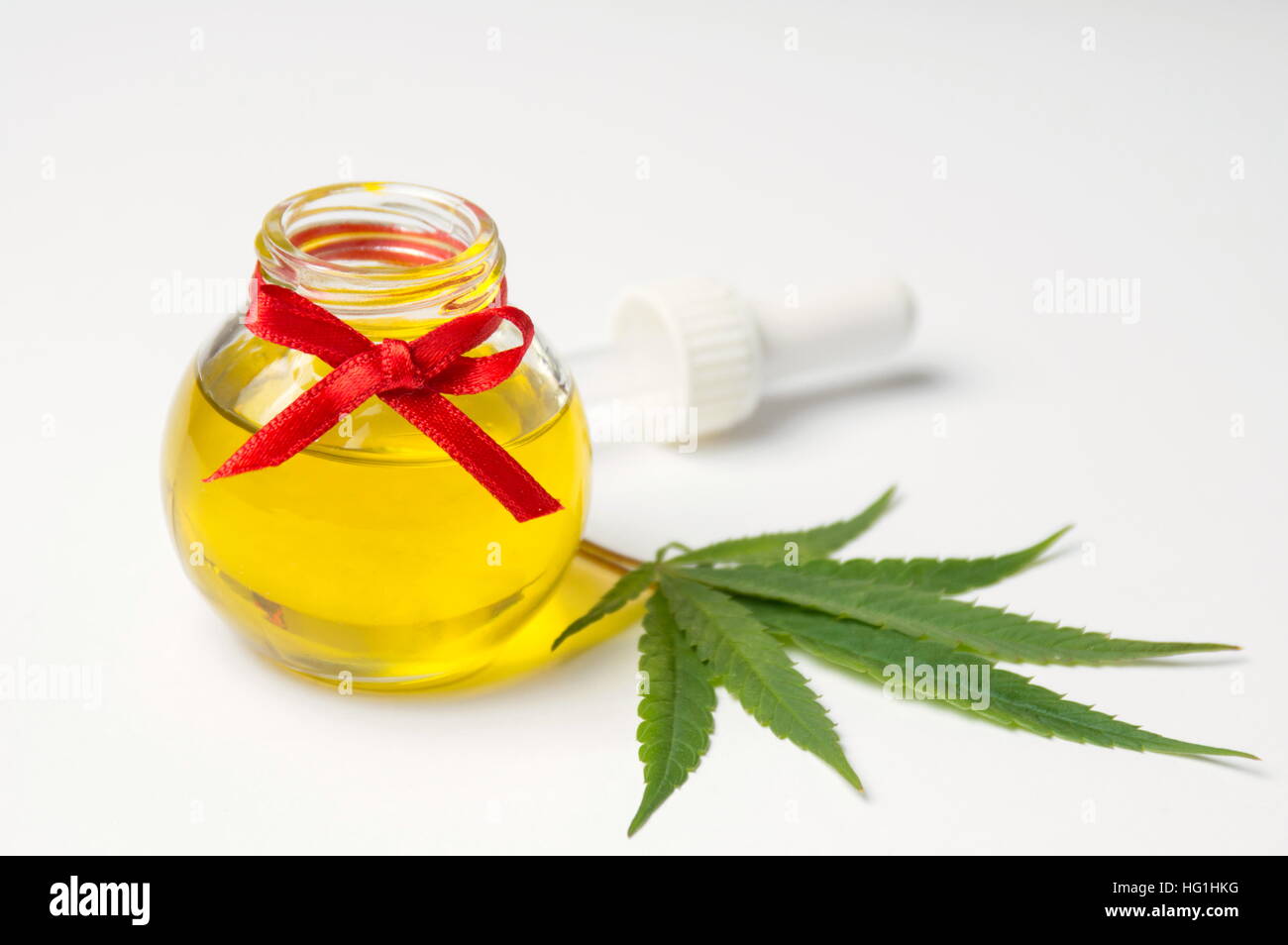 Foglie di cannabis e olio su sfondo bianco Foto Stock