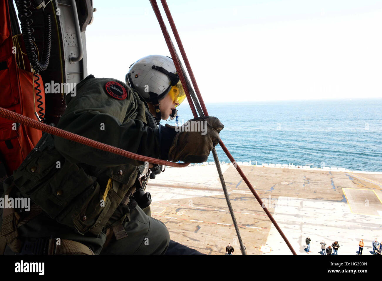 L'equipaggio della Naval AirCrewman gestisce le linee di discesa in un elicottero MH-60S Seahawk mentre si libra sopra la portaerei classe Nimitz USS Nimitz (CVN 68) durante la giornata degli amici e della famiglia nello stretto di Juan de Fuca. Quasi 400 ospiti civili si uniscono all'equipaggio della nave per la giornata mentre la portaerei naviga. Foto Stock