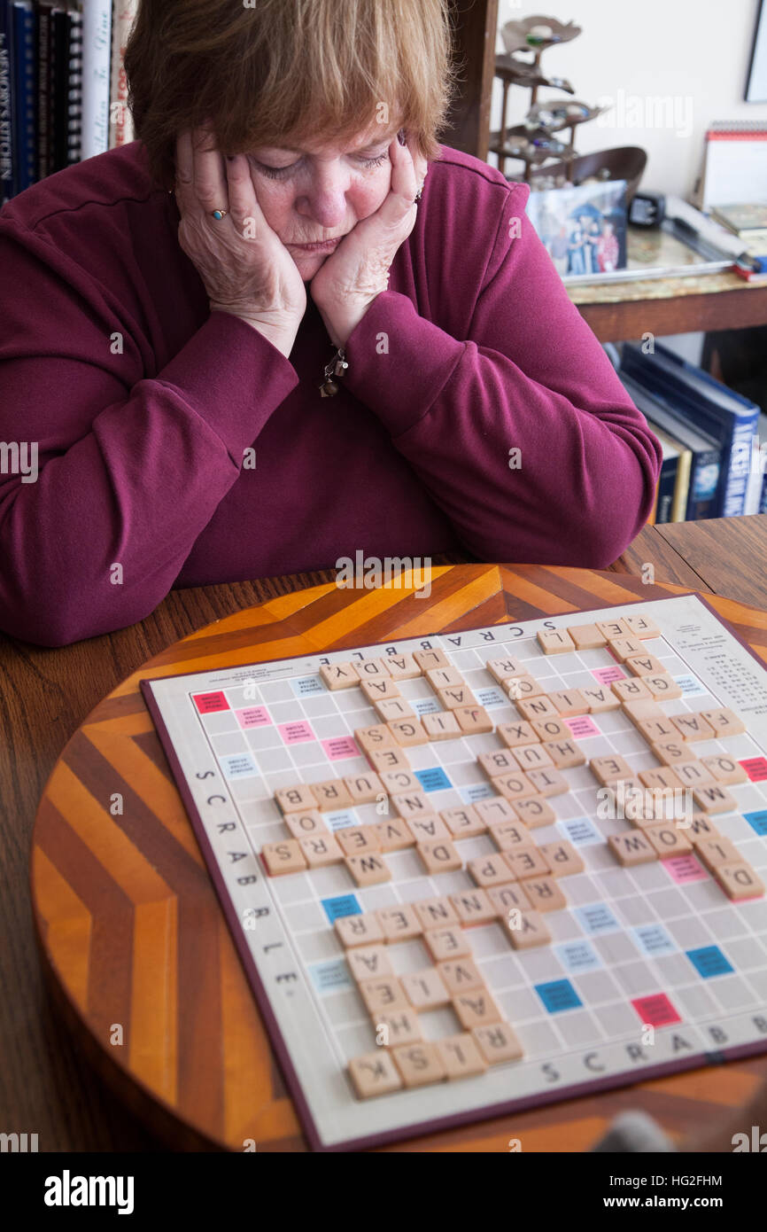 Attraente donna matura studiando la sua prossima mossa in un gioco SCRABBLE. Downers Grove Illinois IL USA Foto Stock