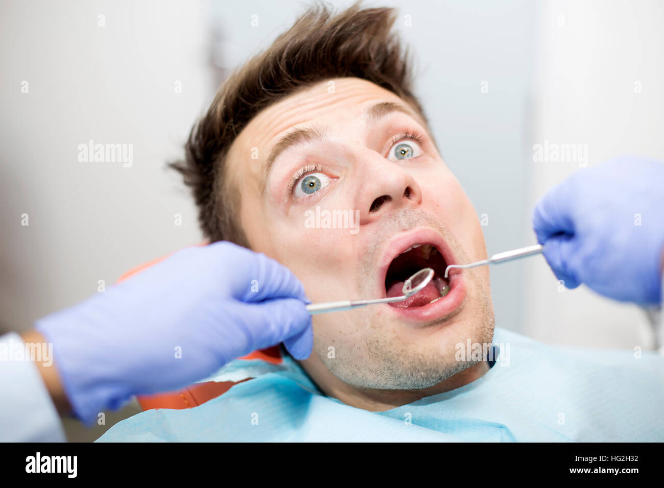 Spaventata giovane alla dentista ufficio durante i denti checkup Foto Stock