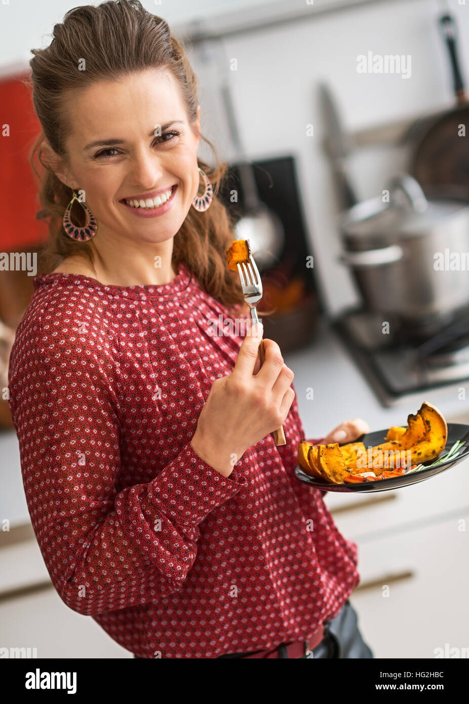 Giovane donna di mangiare la zucca cotta al forno in cucina Foto Stock