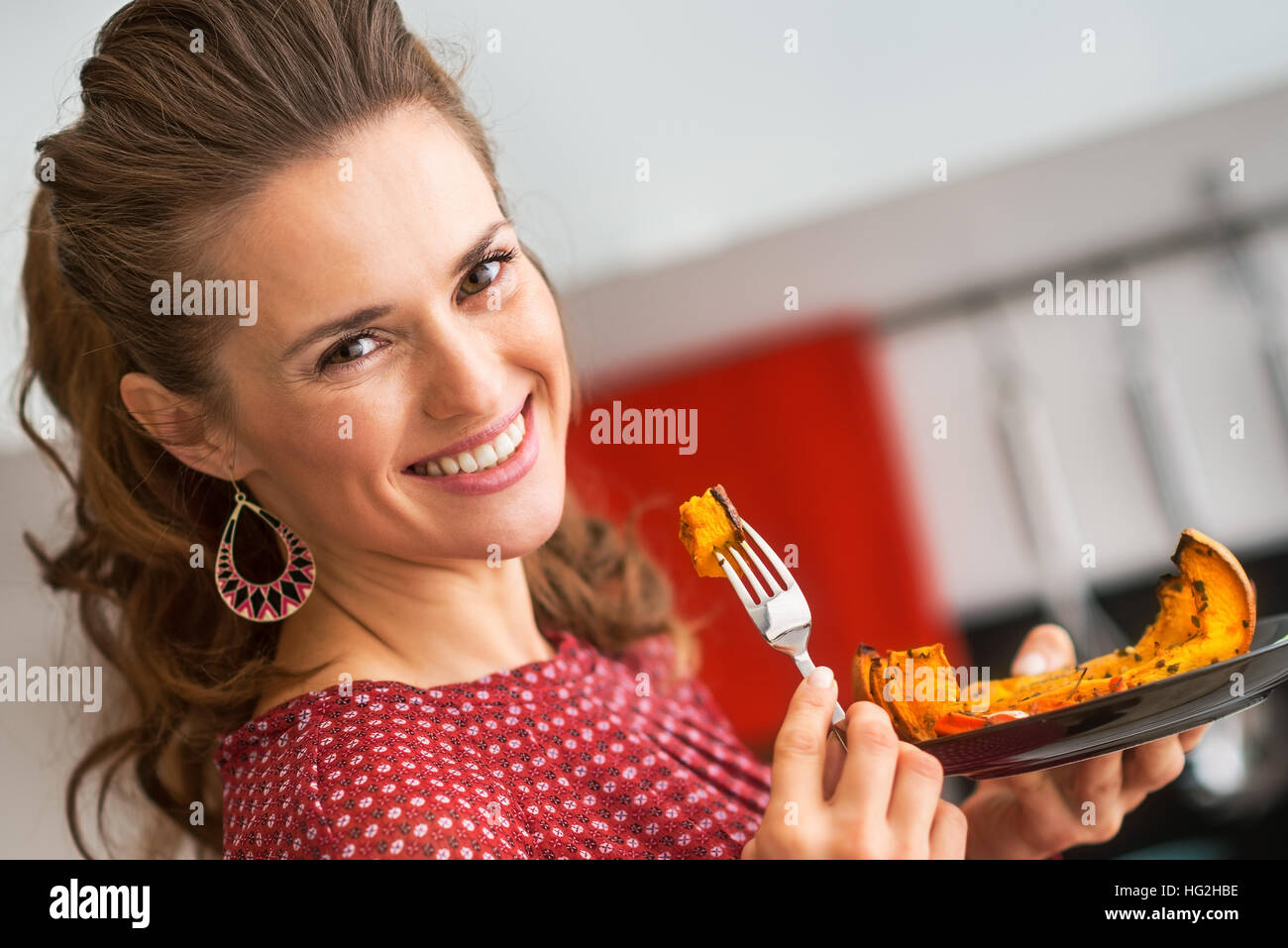 Giovane donna di mangiare la zucca cotta al forno in cucina Foto Stock