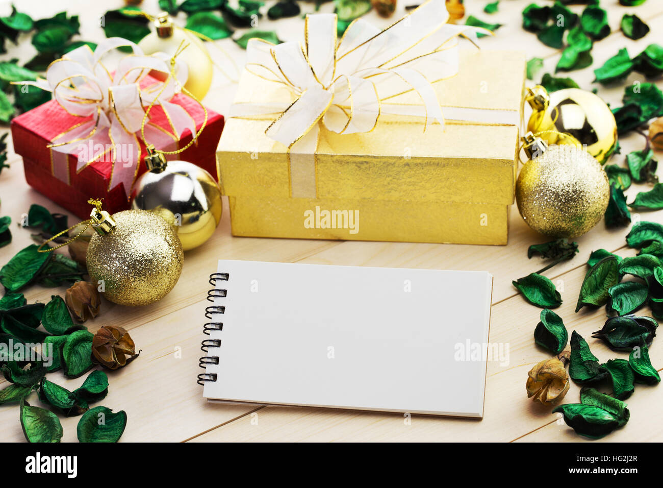 Blank notepad come copia di spazio con confezione regalo e foglie essiccate su vecchie piastre in legno. Una vacanza incantevole sfondo. Foto Stock