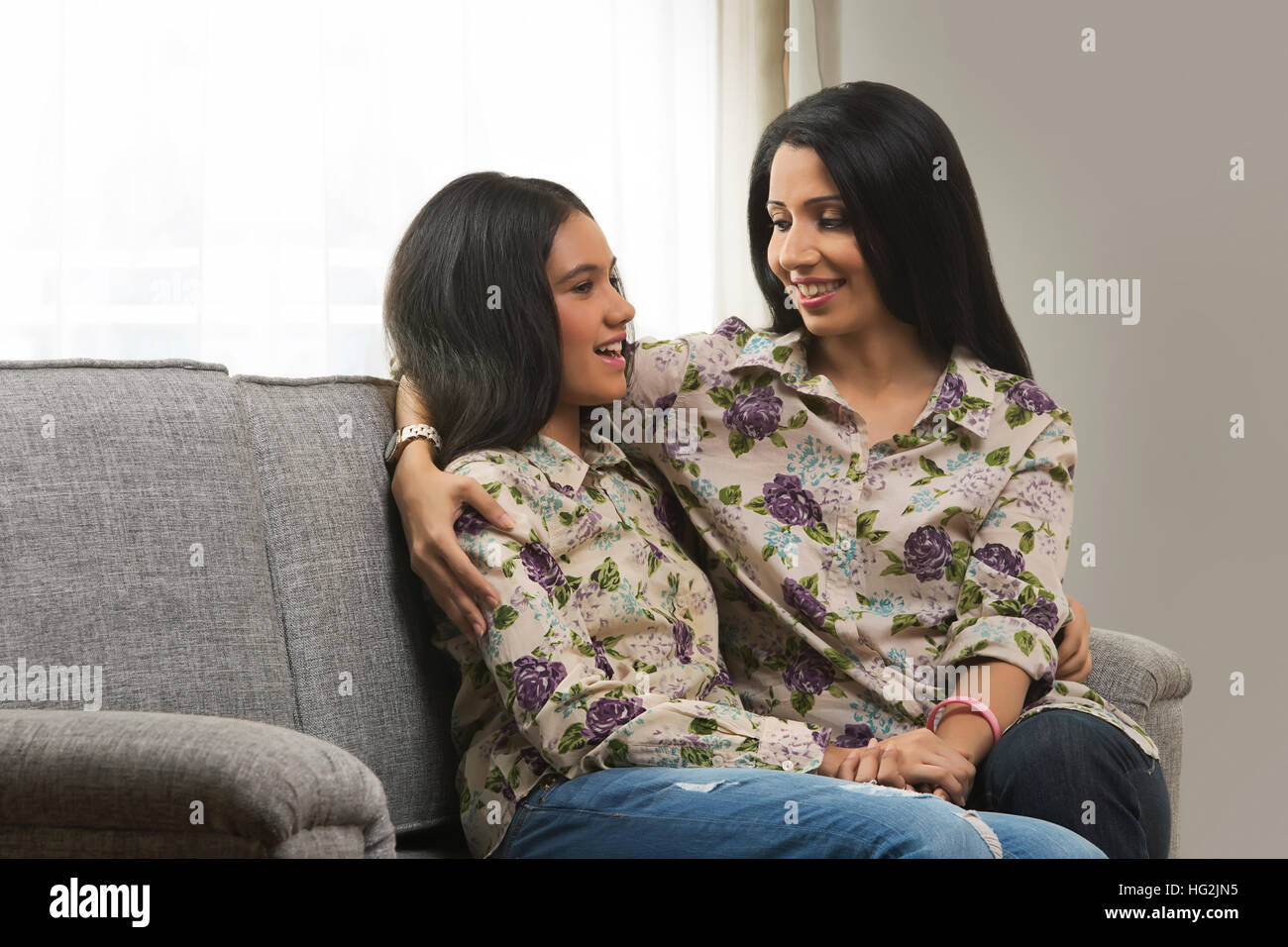 Ritratto di Madre e figlia in corrispondenza abbigliamento avvolgente seduta sul divano Foto Stock