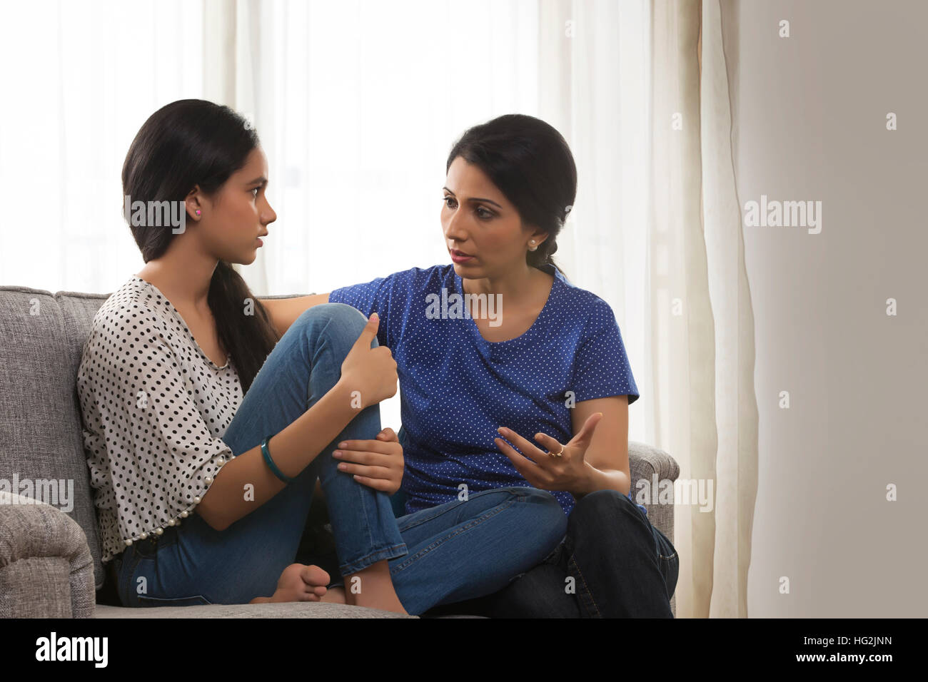 Madre e figlia adolescente conversare in salotto Foto Stock
