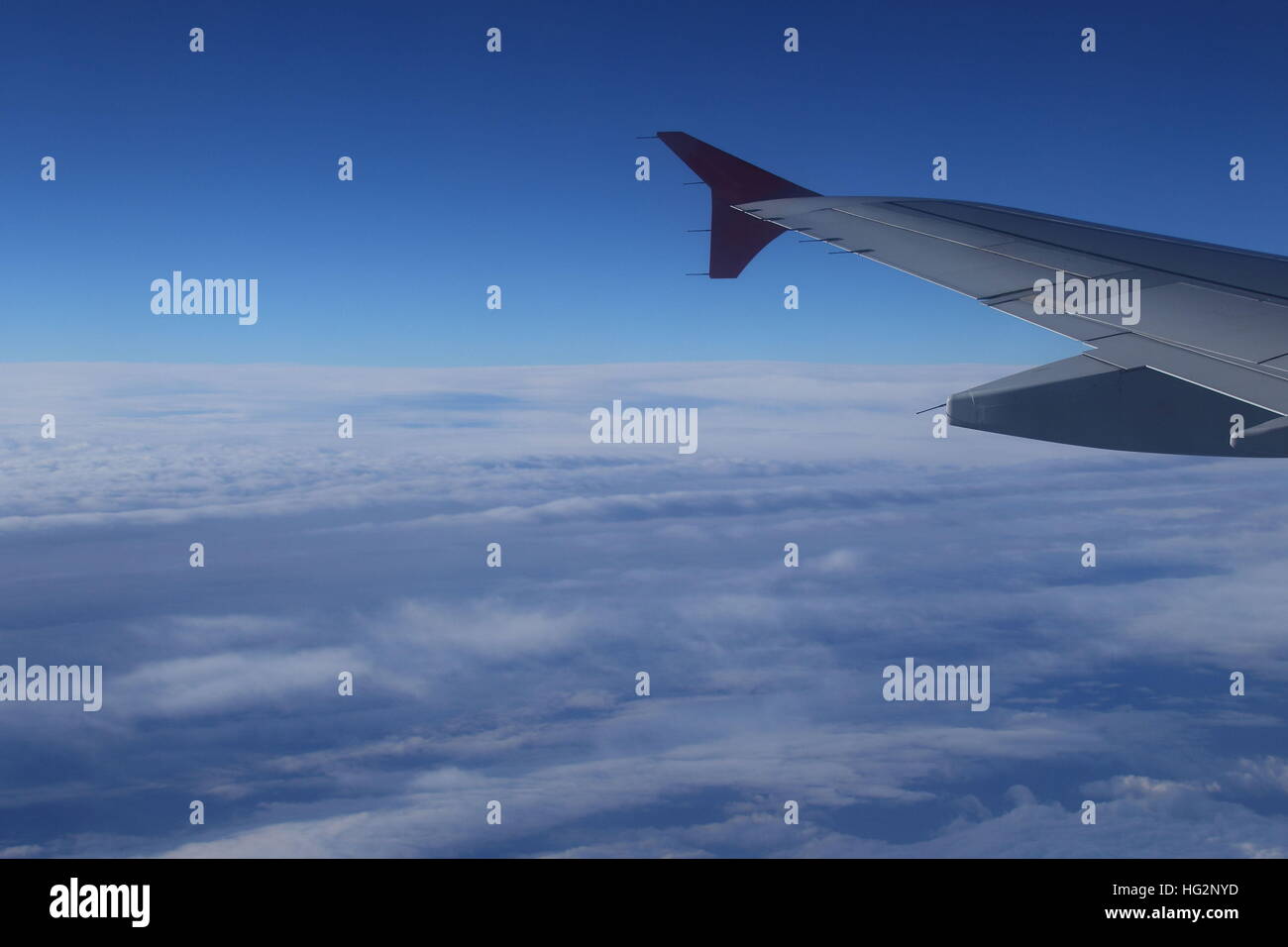 Vista dal lato passeggero nella finestra di aeromobili battenti alto sopra le nuvole in immagine diurna con spazio di copia in formato orizzontale Foto Stock