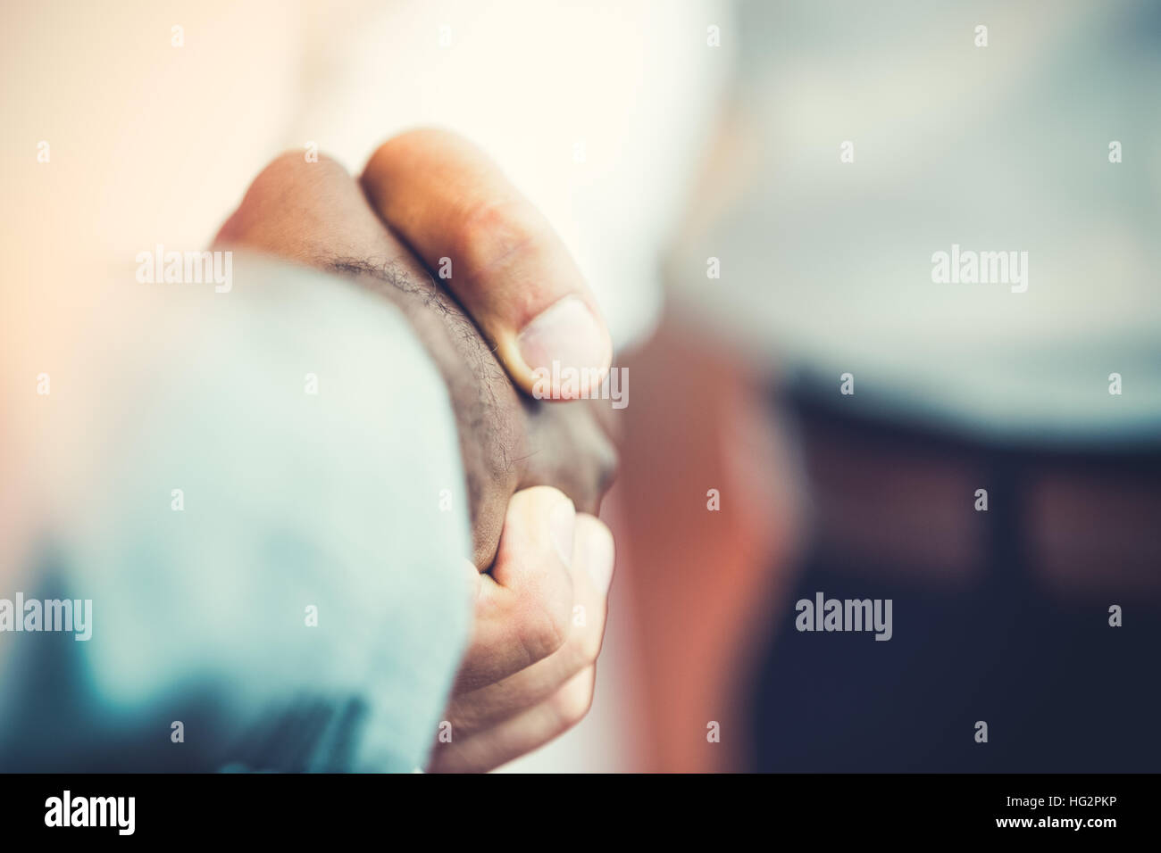 Stretta di mano tra africani e di un uomo caucasico Foto Stock