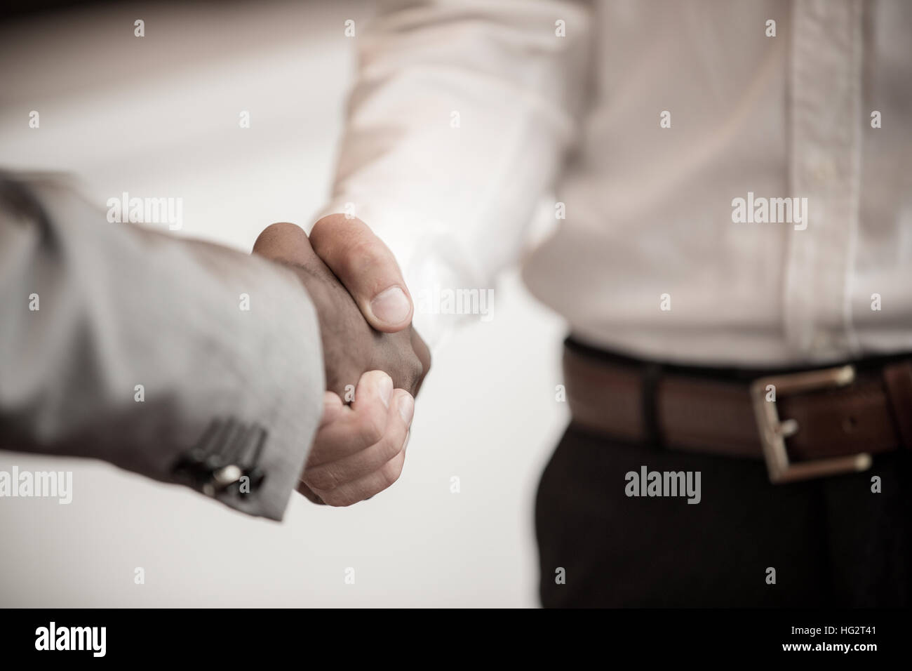 Stretta di mano tra africani e di un uomo caucasico Foto Stock