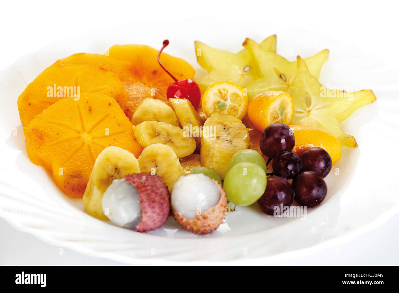 Un piatto di frutta: Star Fruit (carambola), kaki, kumquat, litchi, banane e uva Foto Stock
