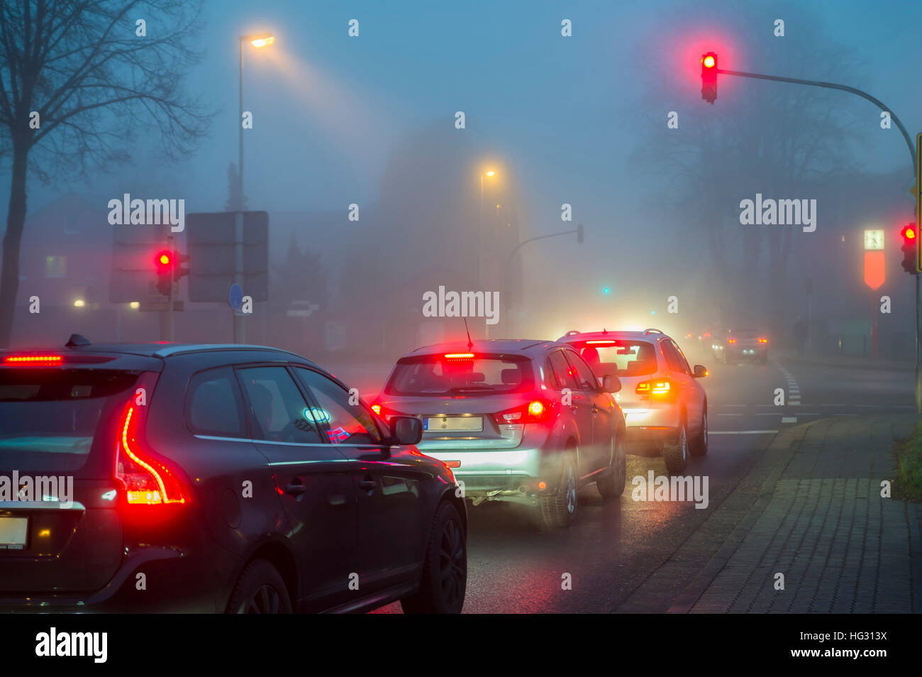 Auto in corrispondenza di una luce di colore rosso in presenza di nebbia di notte, traffico, Grevenbroich, Nord Reno-Westfalia, Germania Foto Stock