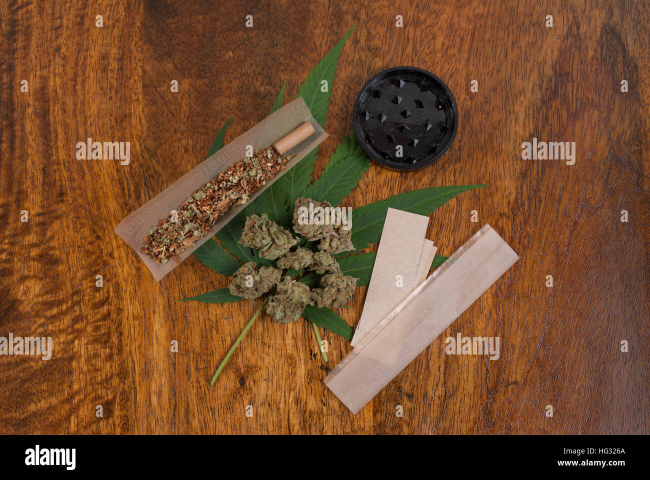 La Cannabis sativa weed leaf e boccioli di fiori su sfondo di legno con grindr e grandi fumatori paper, spazio di copia Foto Stock